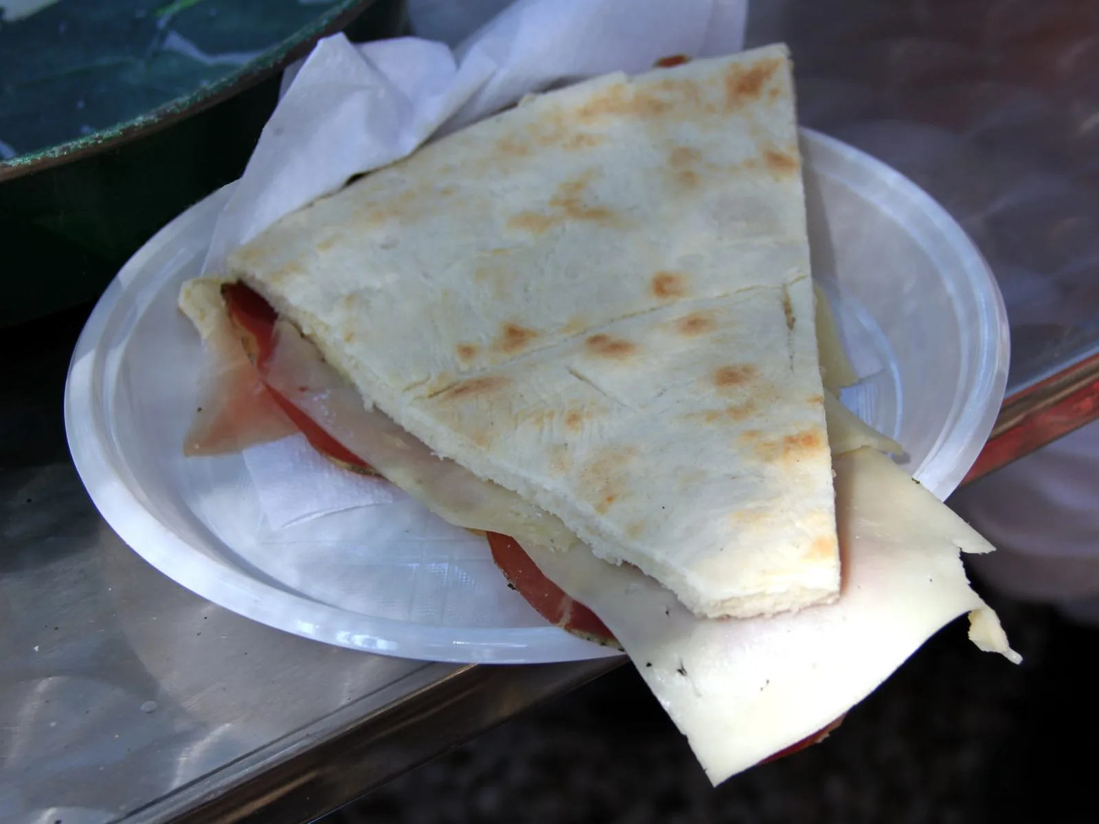 Uno spicchio di torta al testo farcito con prosciutto e formaggio, servito su un piatto